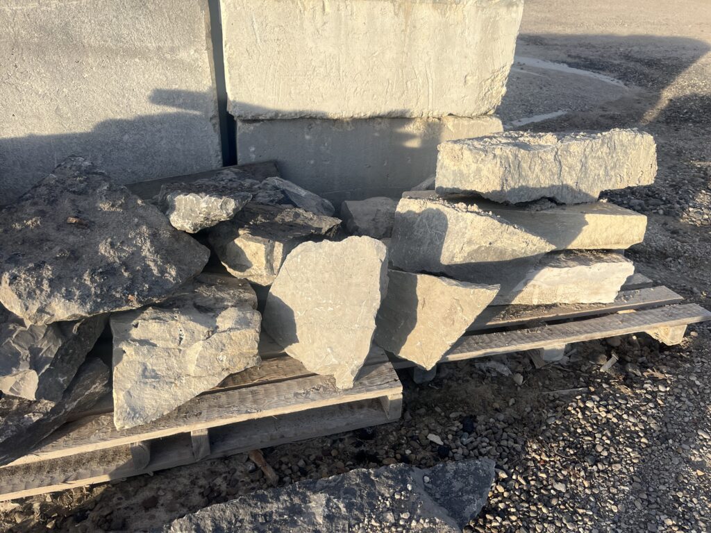 Remnant rocks available Stack of remnant natural stones on a pallet, available for purchase at $0.15 per pound, commonly used as accents in landscaping projects.